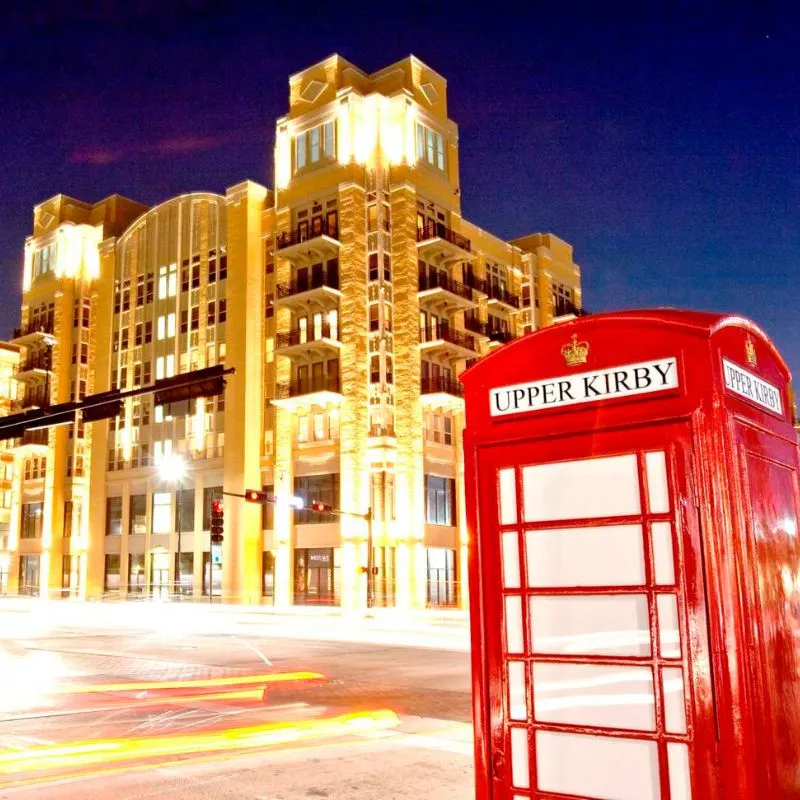 Illuminated city corner with red phone booth at night.
